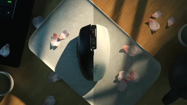 Razer Orochi V2 black wireless mouse on a desk beside a laptop